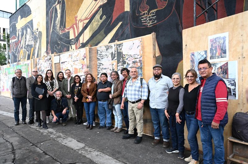 Artistas plásticos mexicanos posan junto a un mural.