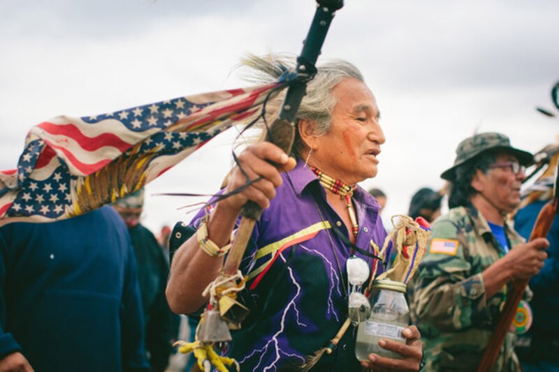 Indígena americano con tocado de plumas y bandera de los Estados Unidos