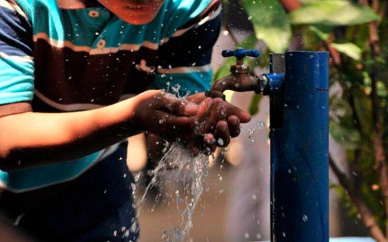 Niño se lava las manos en una llave de agua pública
