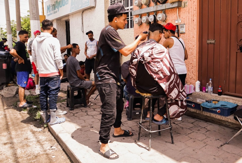 Un barbero corta el pelo a un cliente en la calle.