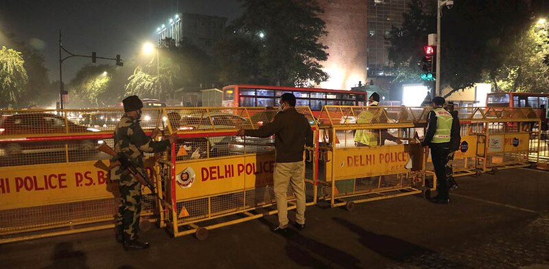 La policía de Delhi detiene a un hombre en un puesto de control durante la noche