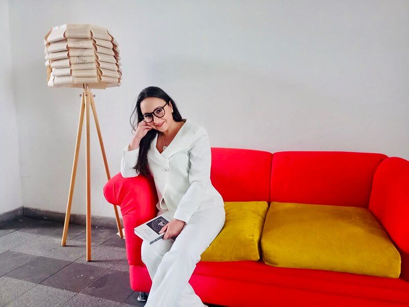 Mujer leyendo un libro en un sofá rojo