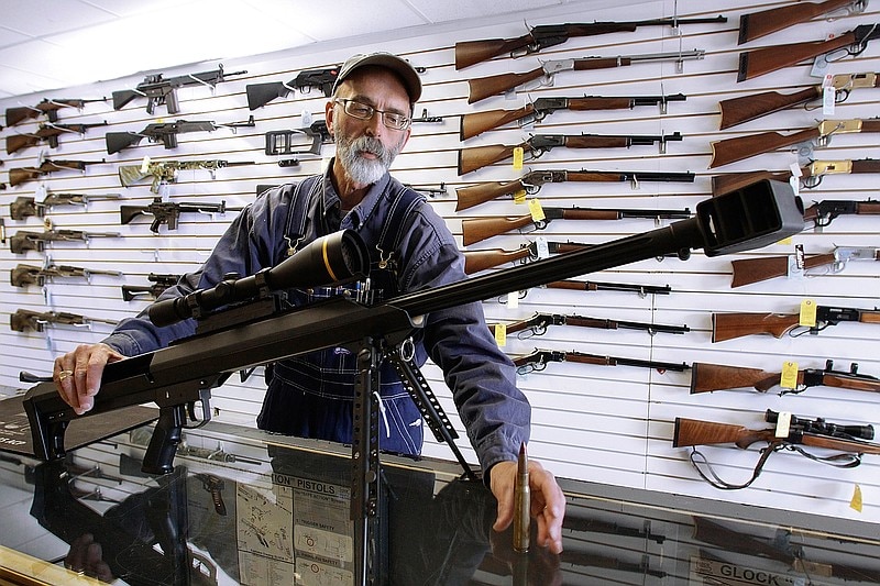 Un hombre sostiene un rifle en una tienda de armas.