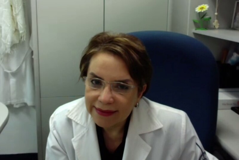 Doctora en bata blanca sonríe a la cámara