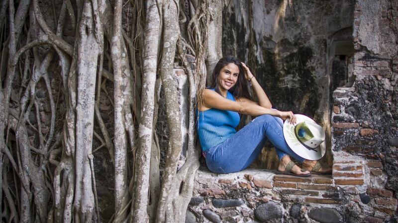 Mujer sentada en una piedra junto a un árbol
