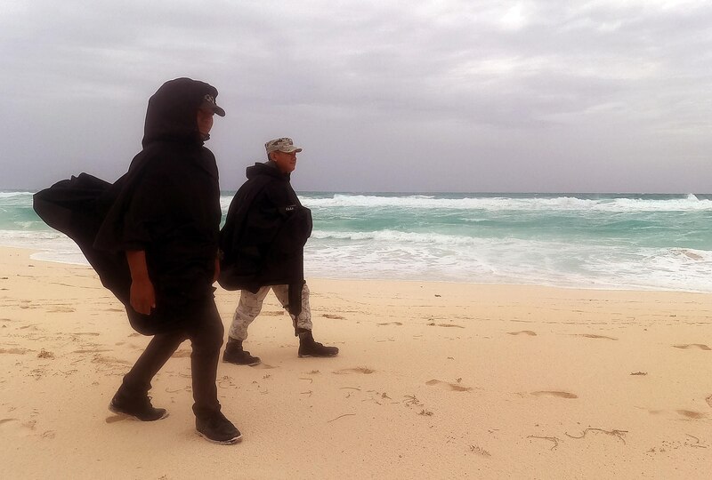 Dos personas caminan por la playa en un día lluvioso