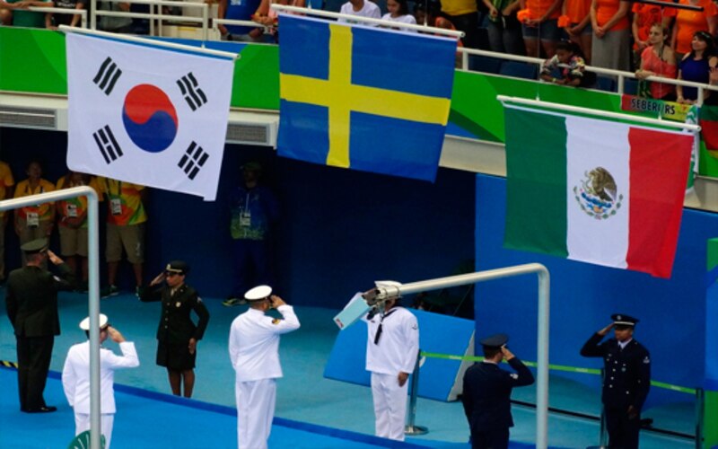 Militares saludando banderas de Corea del Sur, Suecia y México