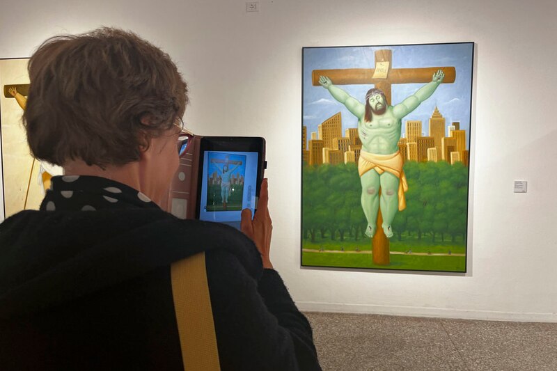 Mujer tomando una foto de una pintura de Jesucristo crucificado