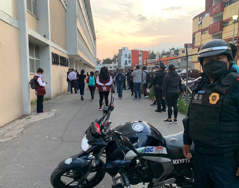 Agentes de la policía custodian una fila de personas que esperan para entrar a un edificio.