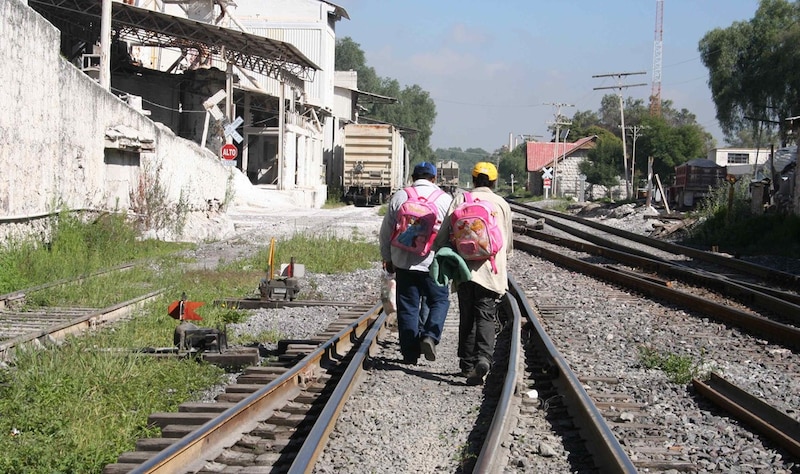 Dos hombres caminan por las vías del tren